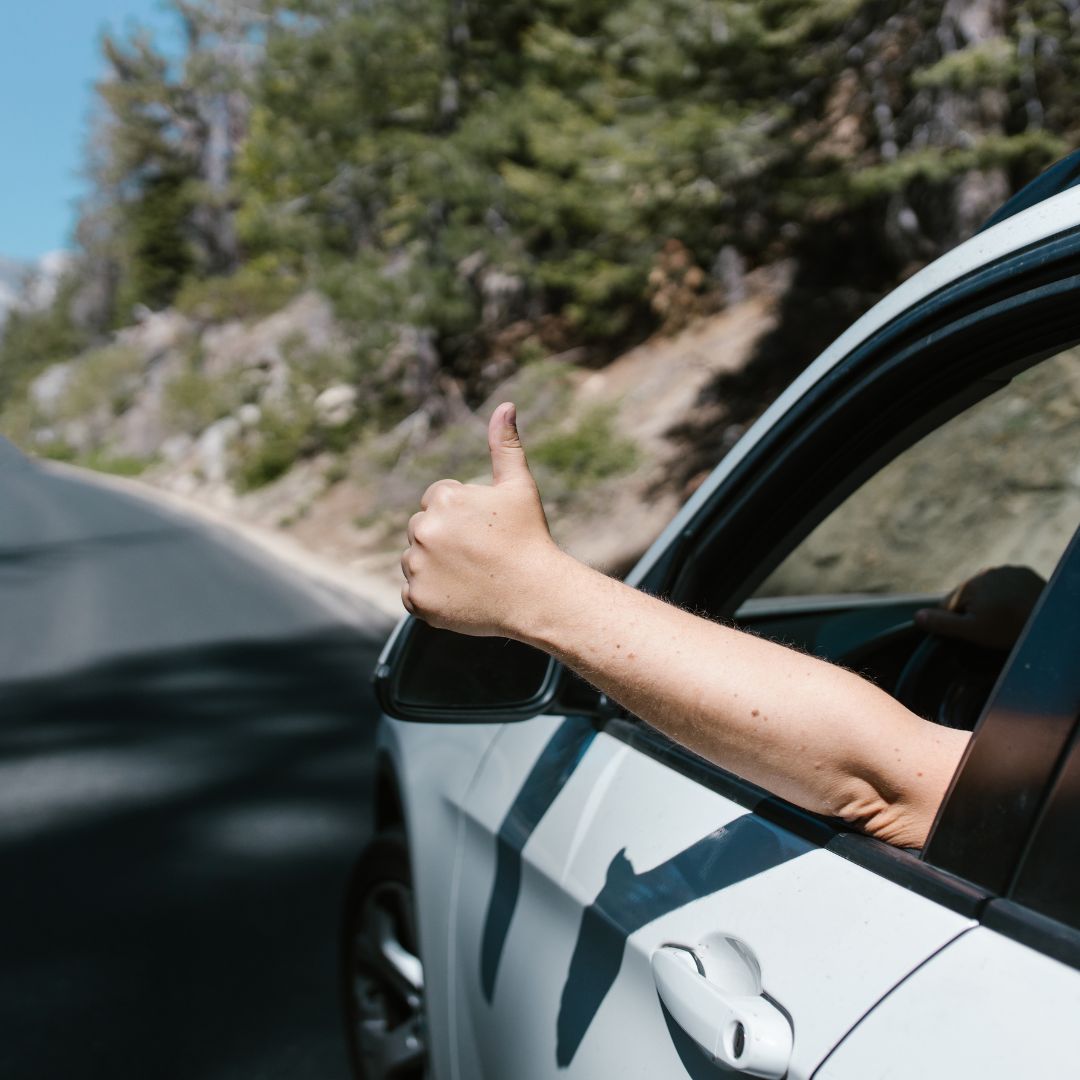 man giving thumbs up out car window